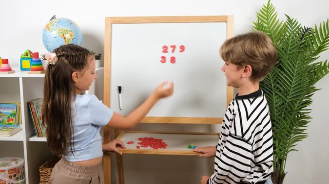 High-quality 4k video footage of elementary students practicing vertical addition on a whiteboard. Young girl and boy calculating math exercise in classroom for education concept.