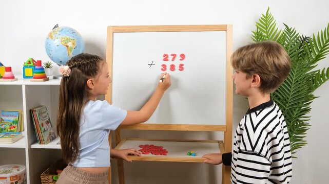 Professional 4k video footage of two young students collaborating on arithmetic math task. Cute boy and girl learning numbers at home or school for interactive educational media.