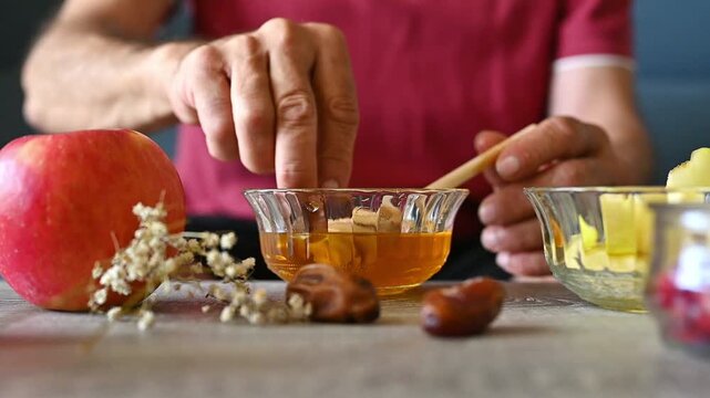 Jewish Man Drizzling Honey Over Sweet Date for Rosh Hashanah, Traditional New Year Food and Shana Tova Blessing