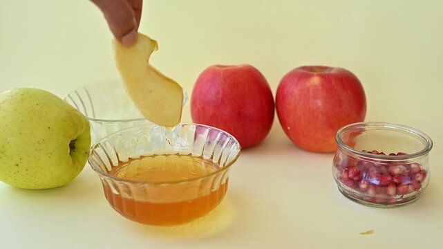 Woman's Hand Dipping Apple Slice in Honey for Rosh Hashanah, Jewish New Year Tradition, Shana Tova Celebration