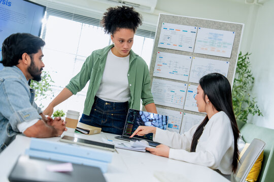Three colleagues of different backgrounds gather closely around a tablet, engaged in a focused discussion of business data a genuine portrait of diverse teamwork and inclusive workplace collaboration