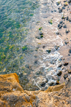 rock texture at the sea. ocean coast background. transparent water. calm wave and seaweed