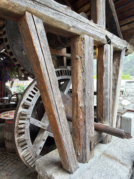 An old wooden waterwheel in a rustic setting with stone walls
