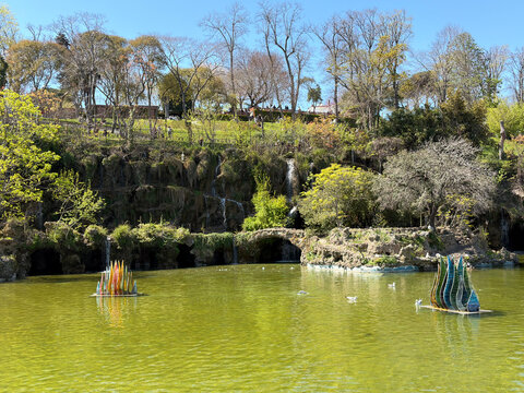 A serene pond surrounded by lush greenery and vibrant sculptures
