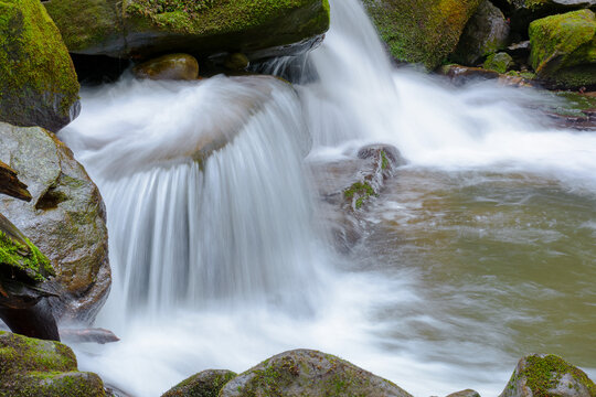 small waterfall closeup. beautiful cascade on the water stream with mossy rock