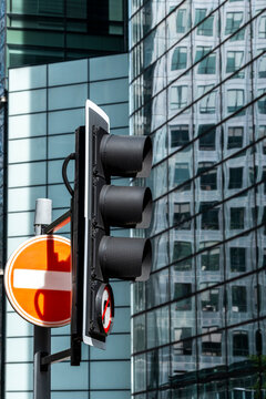 Reflections fill a glass wall behind a traffic signal and red sign along a street in London, England, where the facade carries urban architecture across its surface.