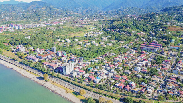 Panoramic aerial view of Batumi suburb coastline in Adjara region with Black Sea shore, residential district and green mountains under clear blue sky Georgia