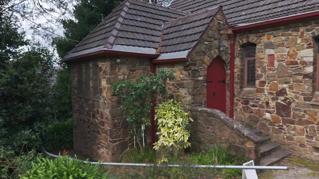 Historic stone church facade with red door in a forest