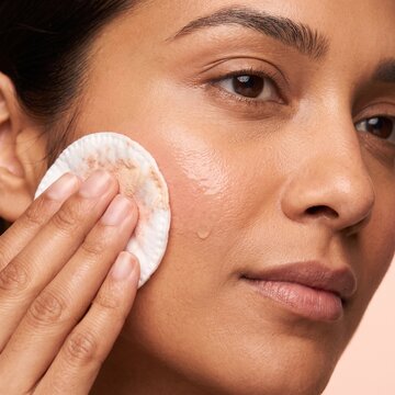Woman Cleansing Face with Cotton Pad During Daily Skincare Routine