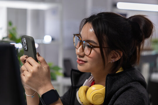 Woman smartphone glasses headphone office smile technology device young asian woman wearing glasses using smartphone with yellow headphone modern office workplace, smiling and focused during