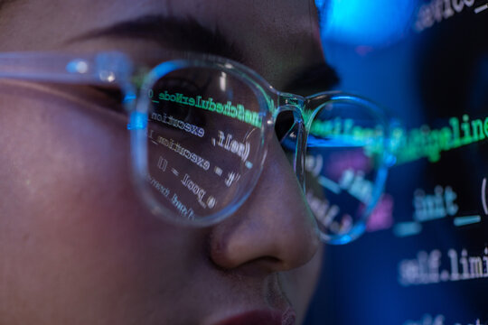 Programmer eyeglass code screen reflection technology face close up, programmer wearing eyeglass with code screen reflection on face during focused software development in dark blue light