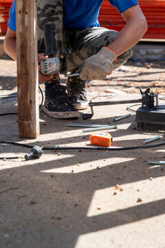 Worker cutting a threaded rod with an angle grinder generating sparks on site