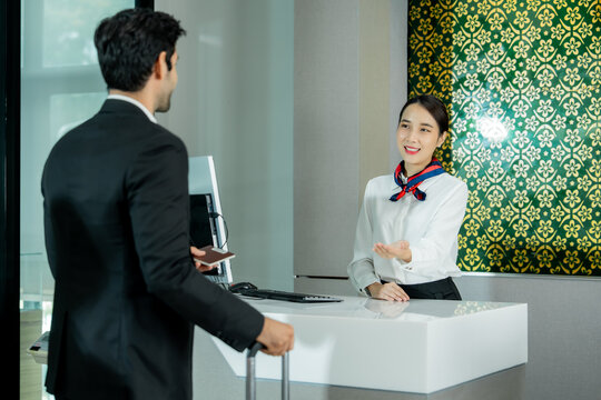 Airport staff welcomes a traveler at the check-in counter while providing assistance with travel documents and luggage in a professional service environment.
