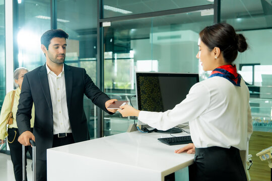A traveler exchanges a passport with an airport representative during check-in showing friendly communication and seamless passenger service.