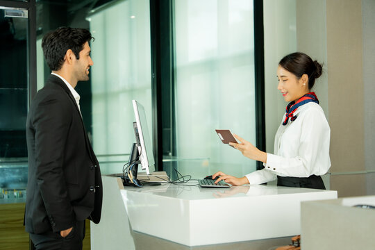 Airport staff assists a passenger at the check-in counter using digital technology to provide efficient travel service and a welcoming customer experience.
