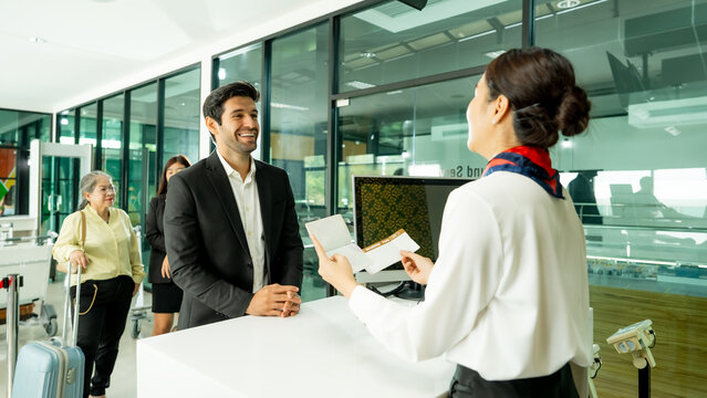 Traveler interacts with airport staff while completing check in with luggage nearby. Strong visual for business travel passenger service and airport experience campaigns.