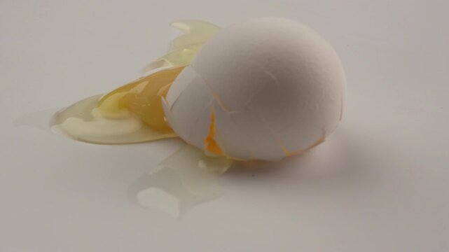 Close-up of chicken egg falls on a white table and breaks
