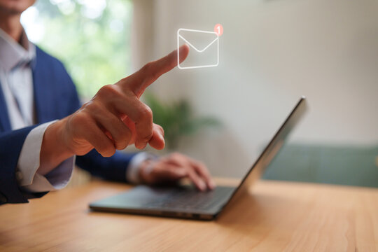 Business professional using a laptop and touching a virtual email notification icon, representing digital communication, online messaging, inbox management, corporate contact and workflow.