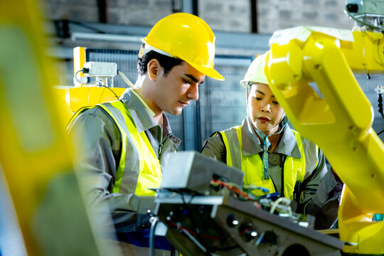 Engineering professionals share knowledge and communicate while working with robotic equipment in a collaborative technology focused environment.
