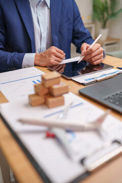 Logistics professional using a digital tablet with shipping documents, packages and aircraft model, representing cargo transport, supply chain planning, freight, export and delivery operations.