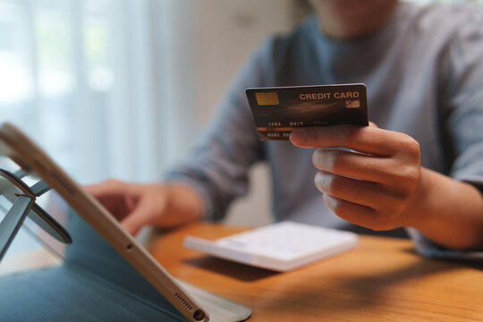 Asian Female doing online payment with a credit card and tablet for digital banking, e-commerce, and personal finance management from home.