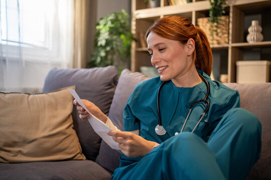 Nurse in scrubs relaxing at home reading letter
