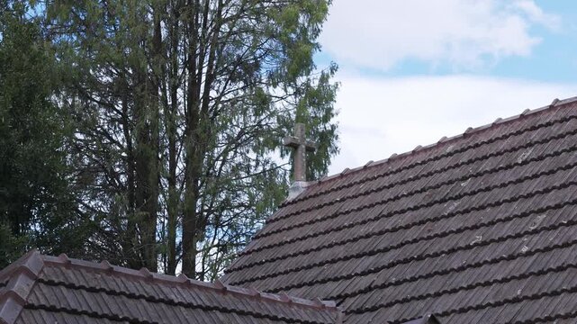 Stone cross on old tiled church roof