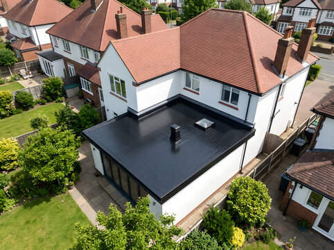 Modern black flat roof extension | Aerial view of white house with garden | Flat roofing membrane installation | Residential property with skylight | Contemporary home renovation