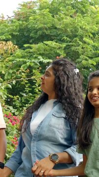 An Indian Asian family of four enjoys a joyful moment outdoors, with parents in their forties and two kids happily walking together, captured from a lower angle