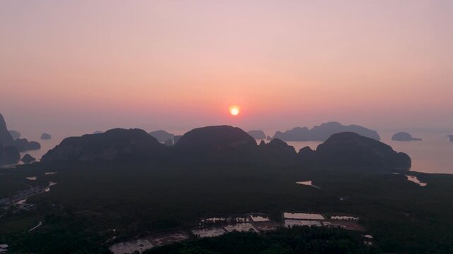 Golden sun rises above the limestone islands and lush mangrove forests of Phang nga bay as seen from the peaceful Samet Nongshe Viewpoint in Thailand