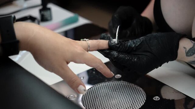 Nail technician files the edges of the nails during the final stage of a manicure. Professional finishing, nail shaping and beauty care concept