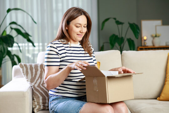 Woman opening personal online shopping parcel. Online shopping at home