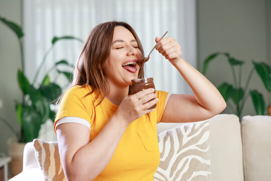 Young woman eating tasty chocolate paste at home