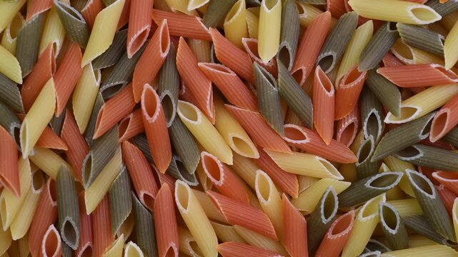 Raw pasta penne tricolore close-up, top view