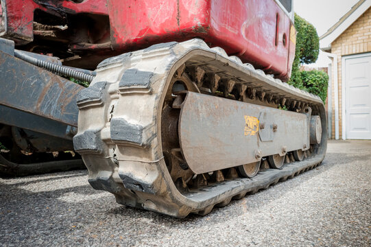Ground level view of the rubber tracks of a mechanical digger and bulldozer showing the many sprockets on the inner tracks. Seen on a private driveway before being excavated.