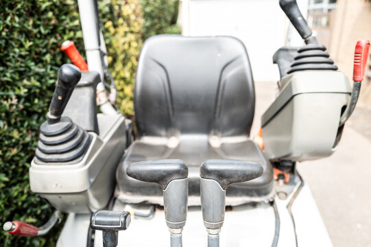 Shallow focus of the drivers steering joysticks and central levers which control the hydraulic scoop. In the background is the drivers seat. Seen on a private driveway before excavation.