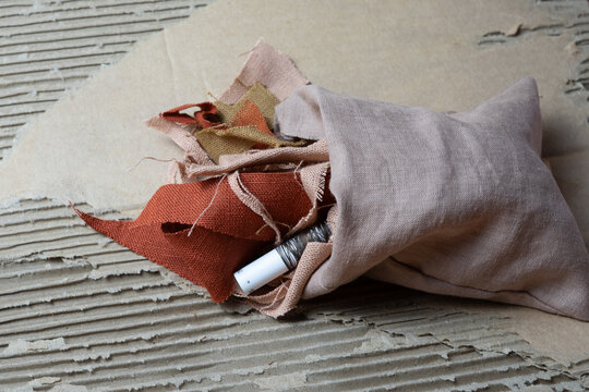 Fabric scraps and thread spool on recycled cardboard, textile waste and circular economy concept
