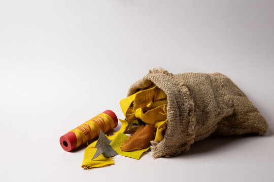 Yellow fabric scraps and thread spool in burlap bag with copy space, sustainable textile waste concept