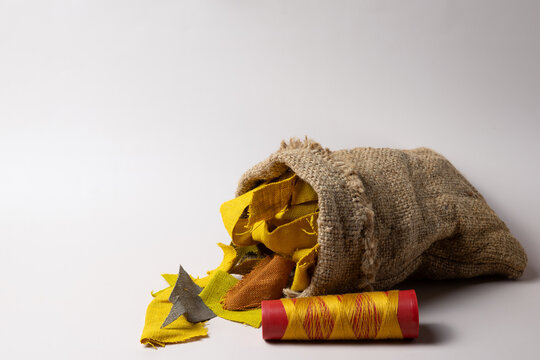 Yellow fabric scraps and thread spool in burlap bag with copy space, sustainable textile waste concept