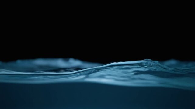 Dark ocean-blue water curls through continuous gentle currents, soft light revealing moving surface texture and subtle depth against near-black with calming natural atmosphere.
