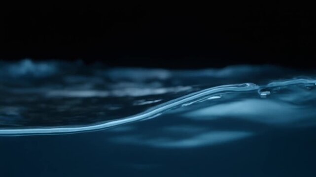 Dark ocean-blue water curls through continuous gentle currents, soft light revealing moving surface texture and subtle depth against near-black with calming natural atmosphere.
