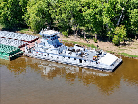 Savanna, Illinois May 11, 2026 Aerial view of the Max A. Fletcher tug boat with barges waiting outside the main channel next to the Mississippi shoreline.