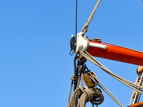 Traditional sailboat rigging with wooden pulley block and hemp ropes against clear blue sky in Antwerpen, Belgi&euml;