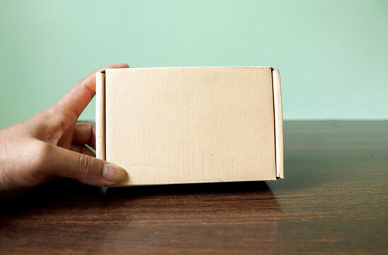 Hand Holding a Small Brown Cardboard Shipping Box