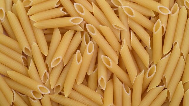 Raw pasta penne rigate close-up, top view