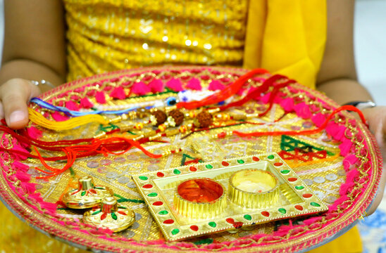 Raksha Bandhan thali with rakhi, rice, kumkum and sweets on a de