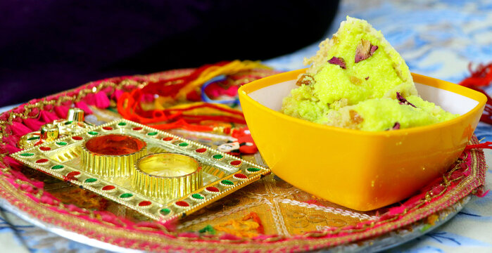 Raksha Bandhan thali with rakhi, rice, kumkum and sweets on a de