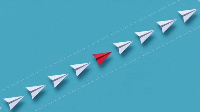 Red paper plane leading a formation of white paper planes along a dashed line on a solid blue studio background