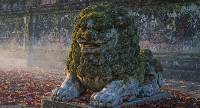 Moss covered stone guardian lion statue on weathered temple path with fallen leaves and mist, atmospheric exterior scene conveying age and spiritual presence