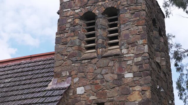 Stone bell tower of a historic church tilting down